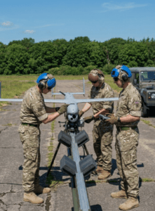 British military personnel preparing a tactical UAV drone for launch on a portable catapult system during a field operation.
