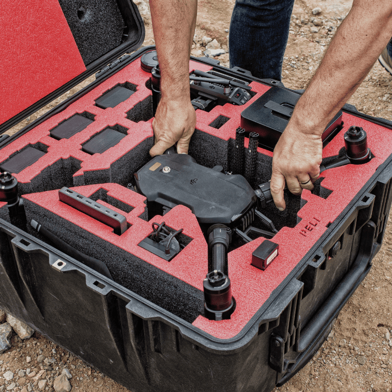 Person handling a foldable professional drone from a custom foam-padded hard case, designed for secure field transport and rapid deployment.