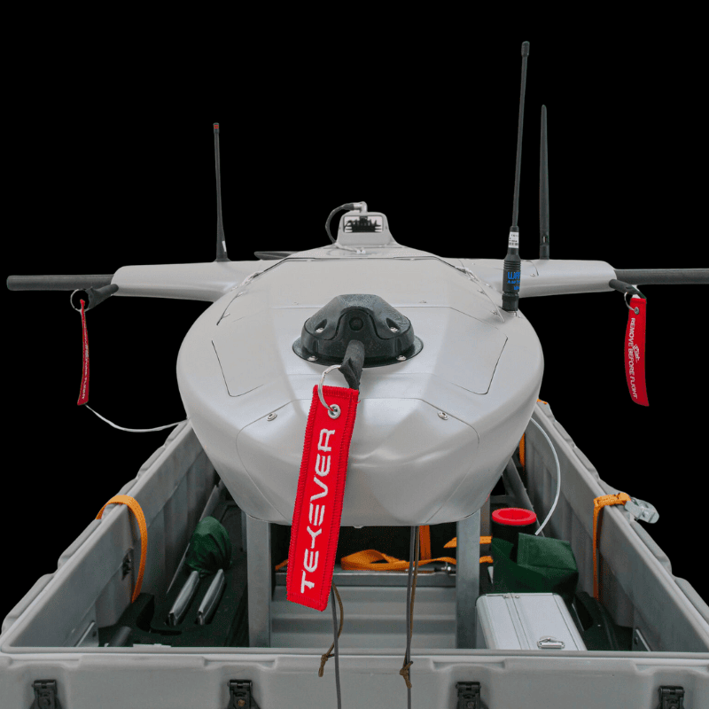 Close-up of a Tekever fixed-wing surveillance drone with antennas and safety tags, secured inside a transport case for deployment.