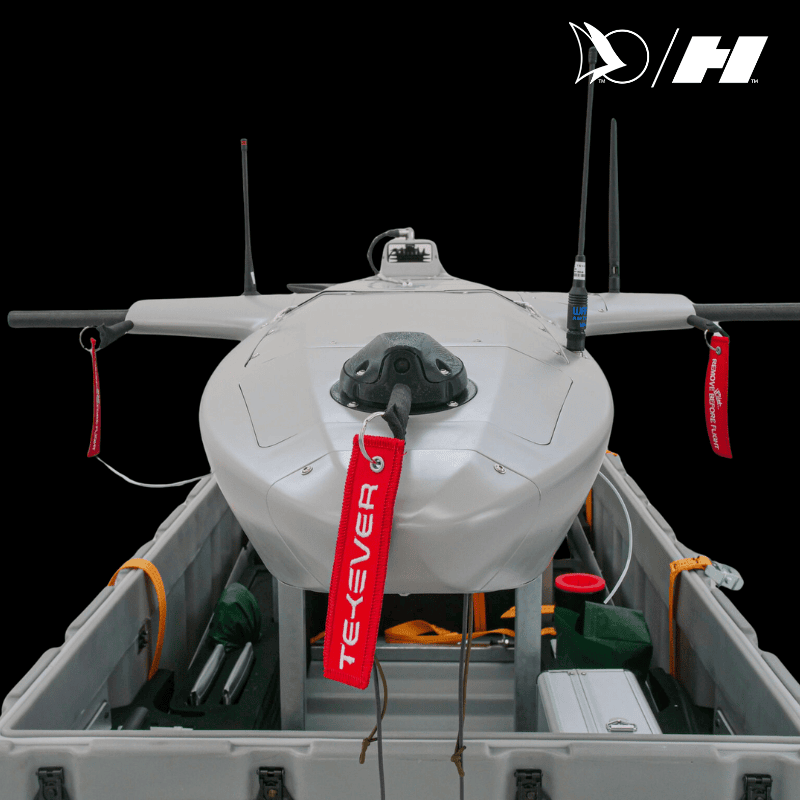 Close-up of a Tekever fixed-wing surveillance drone with antennas and safety tags, secured inside a transport case for deployment.